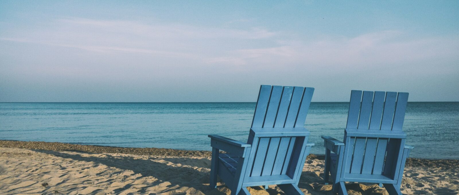 Two beach chairs on a sandy shore