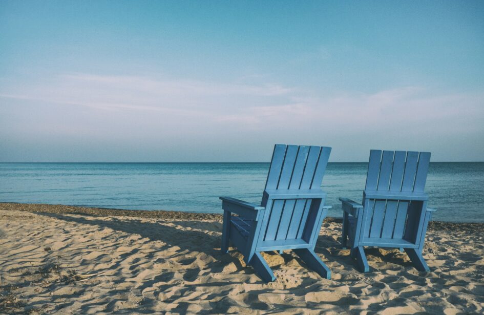 Two beach chairs on a sandy shore