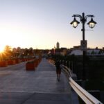 A person walking on a bridge at sunset